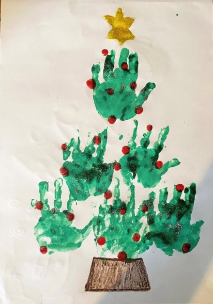 Green coloured handprints in the shape of a Christmas tree, with a gold star on the top.